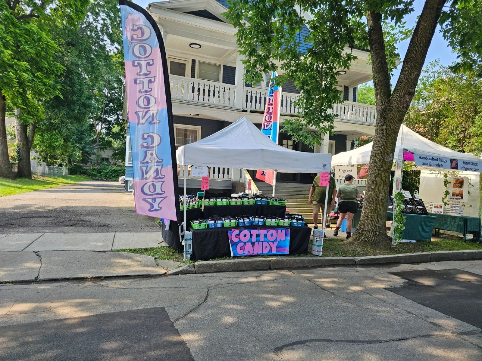 Falanga's tent with tall cotton candy feather flag on a tree-lined Rochester street