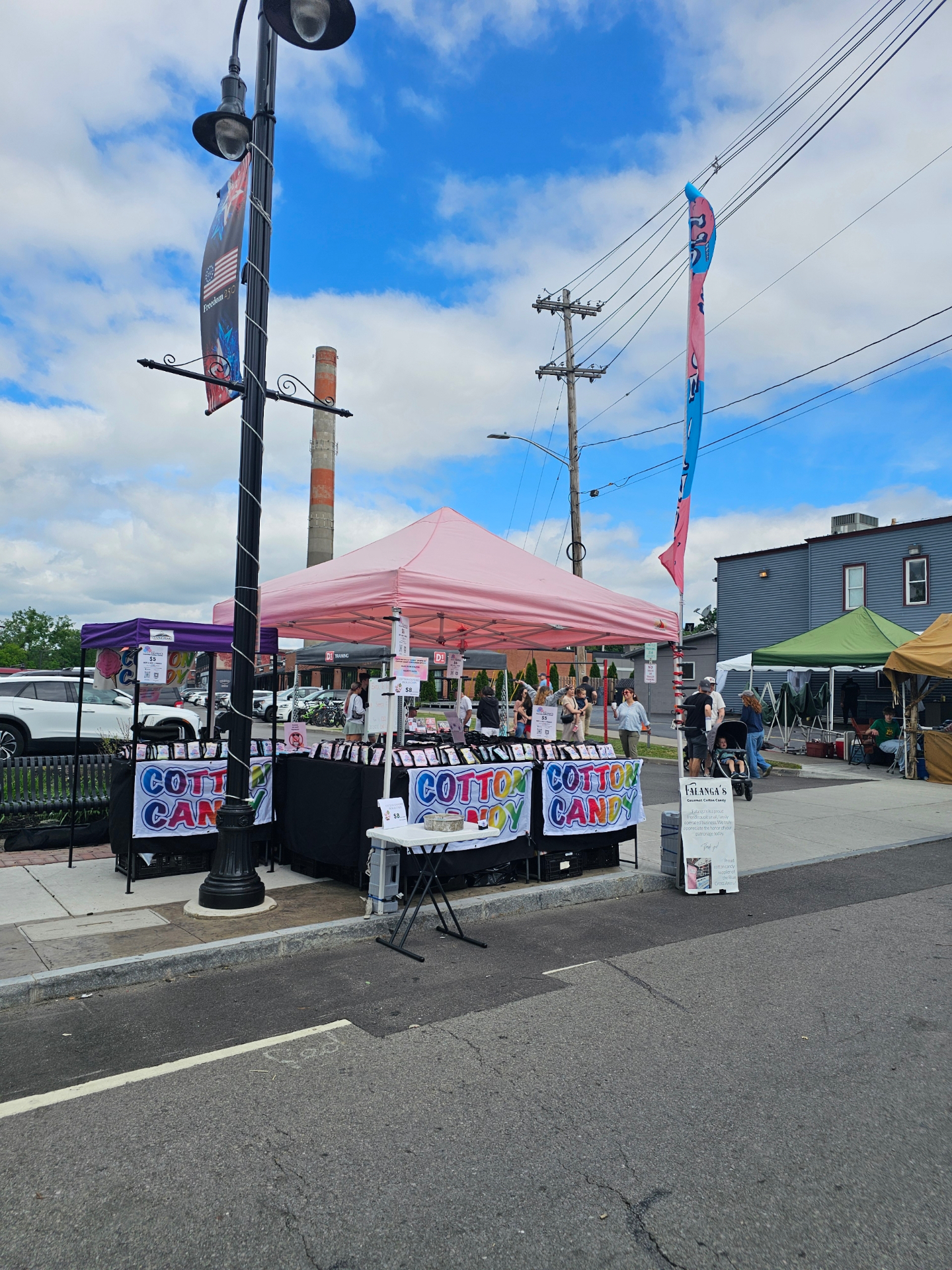 Falanga's pink tent and cotton candy banners set up at a Rochester outdoor street festival