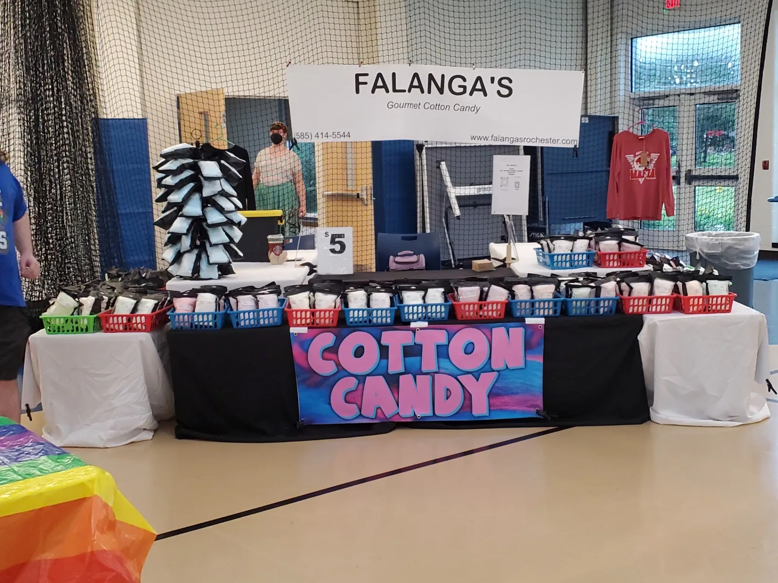 Falanga's booth with cotton candy banner set up inside a school gym event